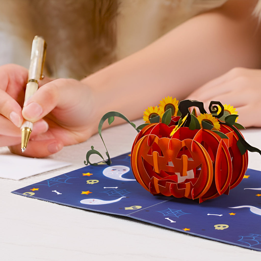 Hand writing on note card placed on open Halloween pop-up pumpkin greeting card