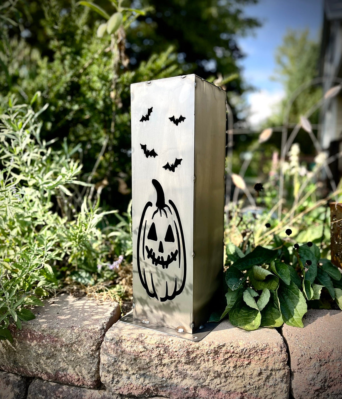 Steel solar pillar light with black jack-o-lantern face and three bat icons