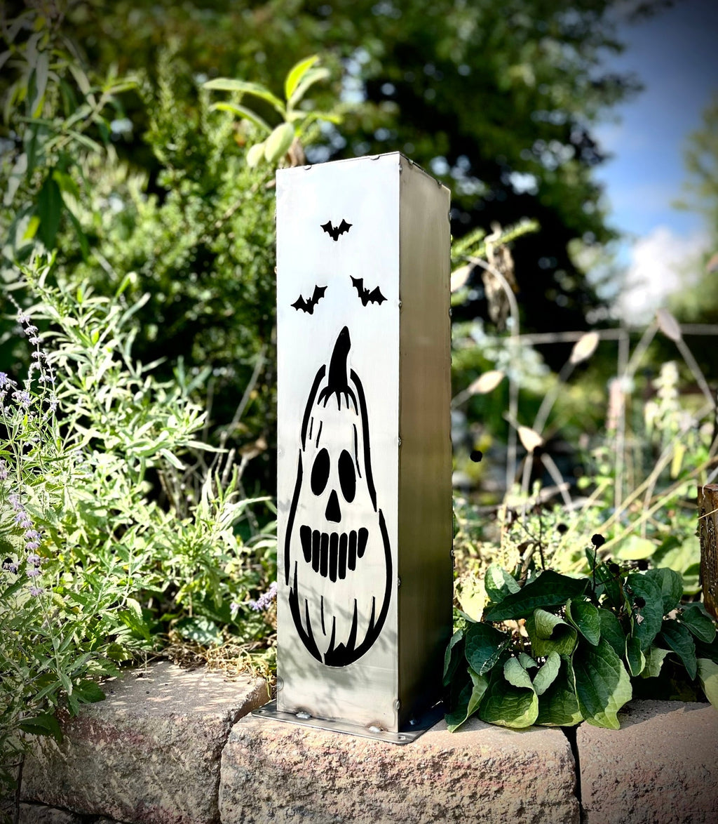 Steel solar pillar light with black jack-o-lantern face on front panel