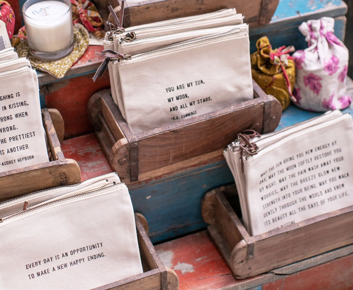 Set of canvas zip pouches with Maya Angelou quote prints in front view.