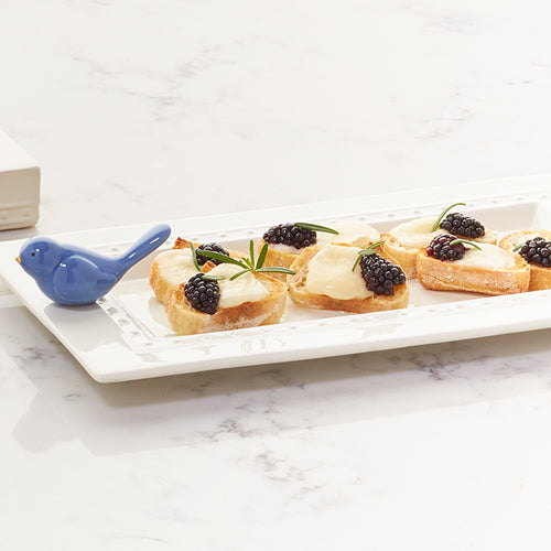Bluebird mini ceramic bird figurine beside small appetizers on a white tray