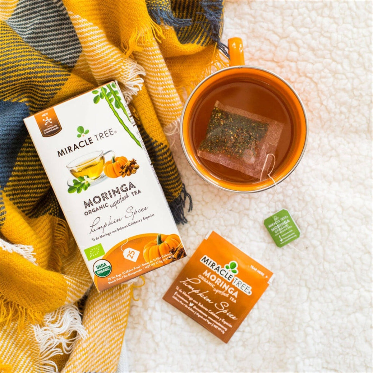 Moringa pumpkin spice tea packets with brewed cup and cinnamon-colored tea