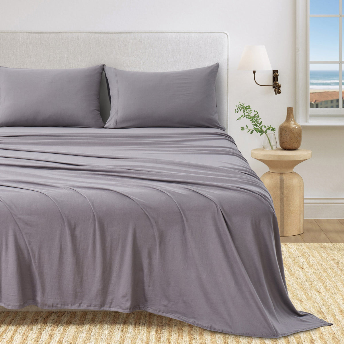 Jersey knit sheet set on bed with pillows, medium grey