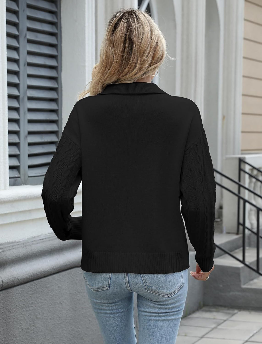 Women’s black cable knit sweater shown from the back with long sleeves and ribbed hem.