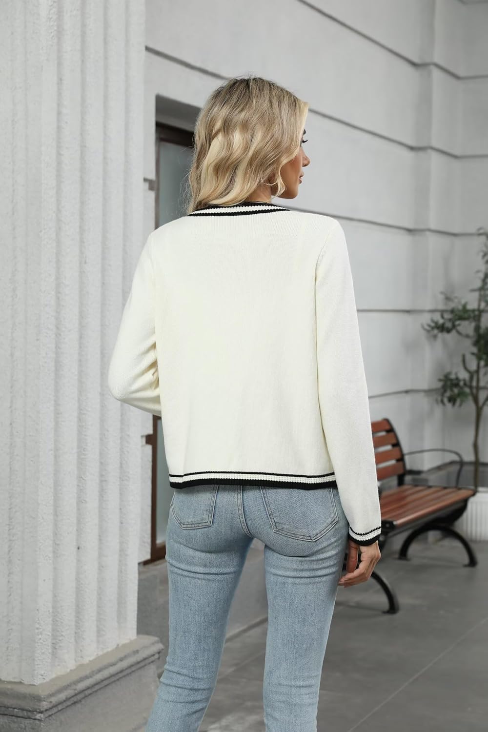 Cream knit cardigan with black-trim hem and cuffs, open-front style from the back.
