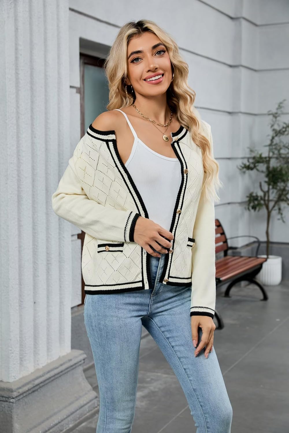 Cream long-sleeve cardigan with black trim and button placket, worn with blue jeans.