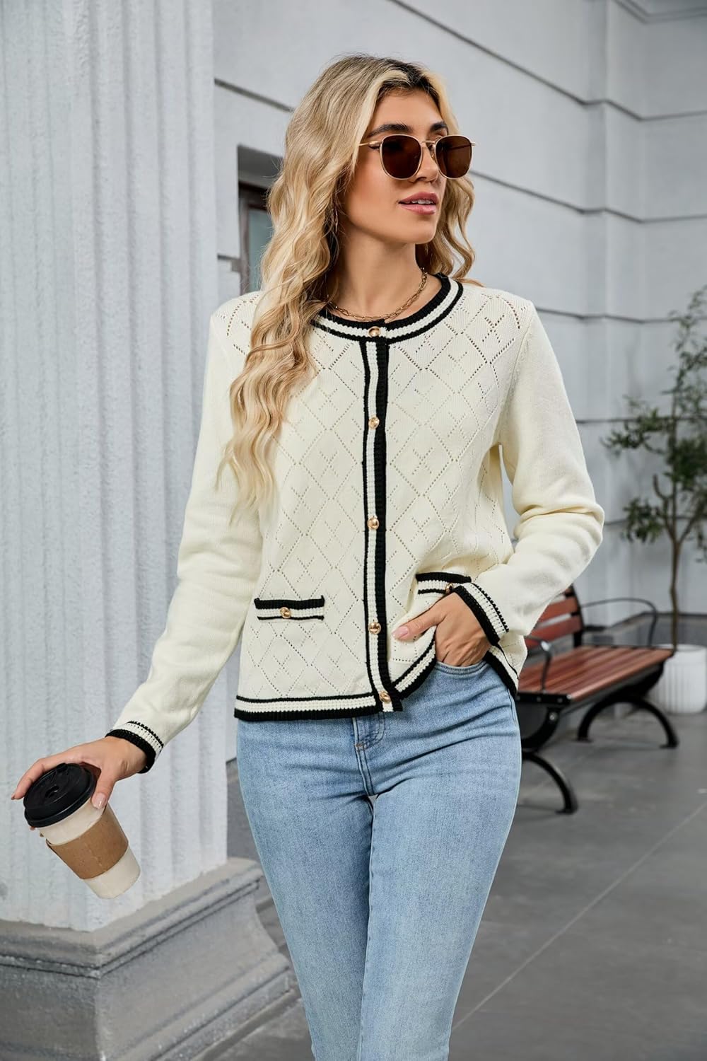 Cream knit cardigan sweater with black trim and front buttons, paired with blue denim.