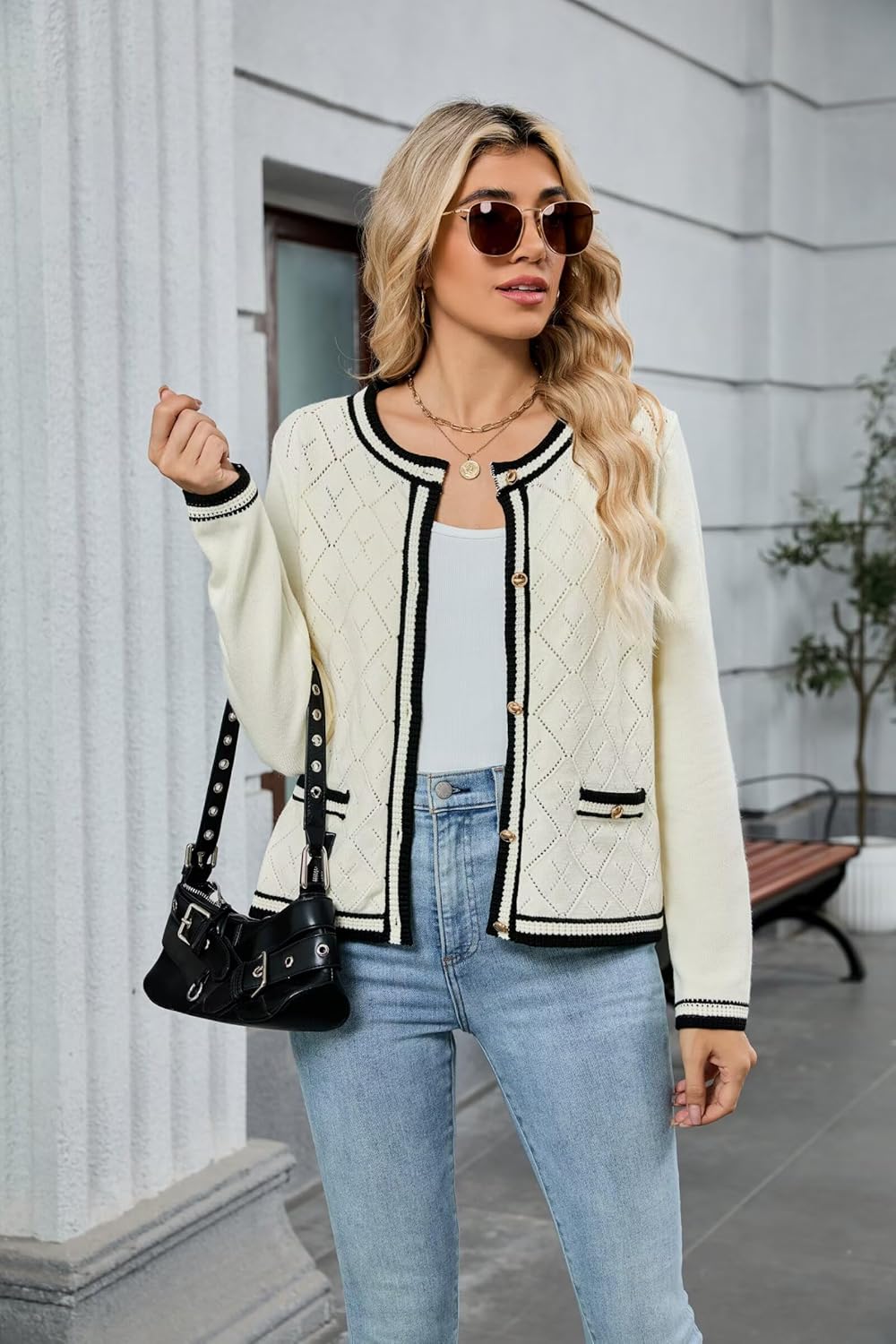 Cream cardigan with black trim, button placket, and diamond knit texture, worn with jeans.